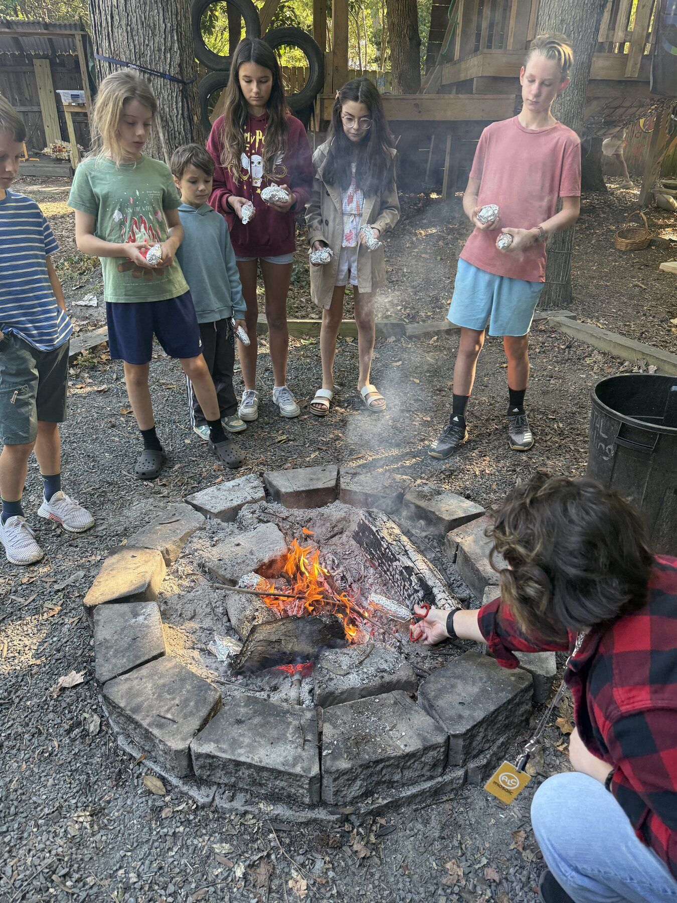 Kids standing round a fire pit while lunch cooks
