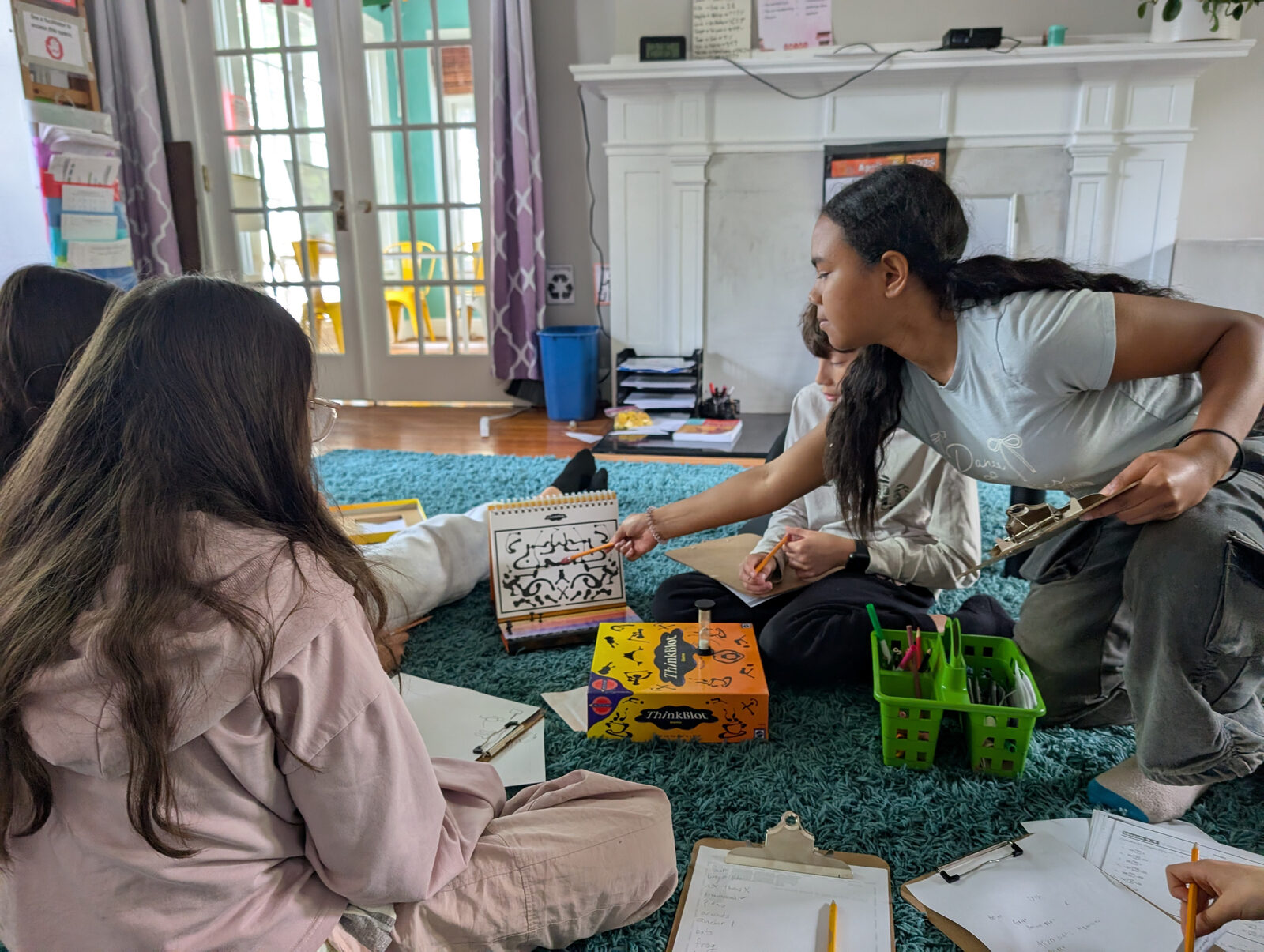 Kids and a facilitator playing a game on the floor of the schoolhouse