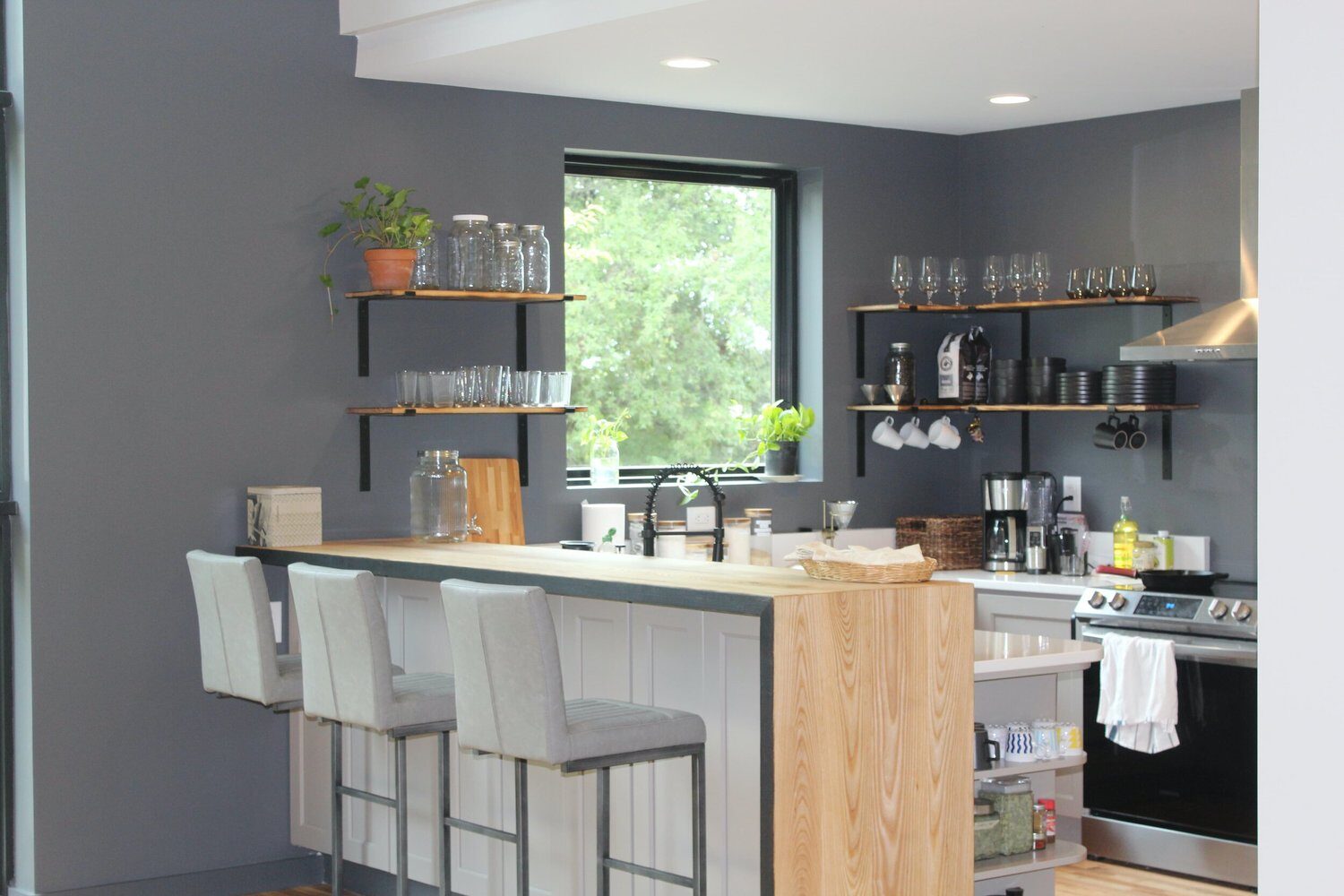 The kitchen: a counter with stools, open shelves and a stove