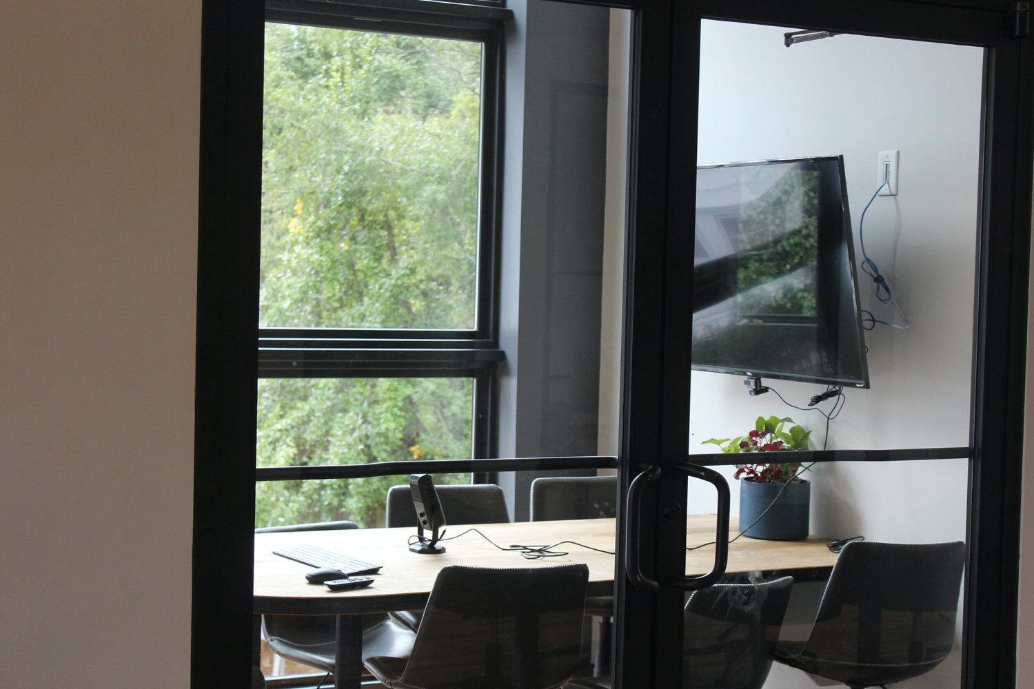 A small conference room with a table, chairs and a wall screen