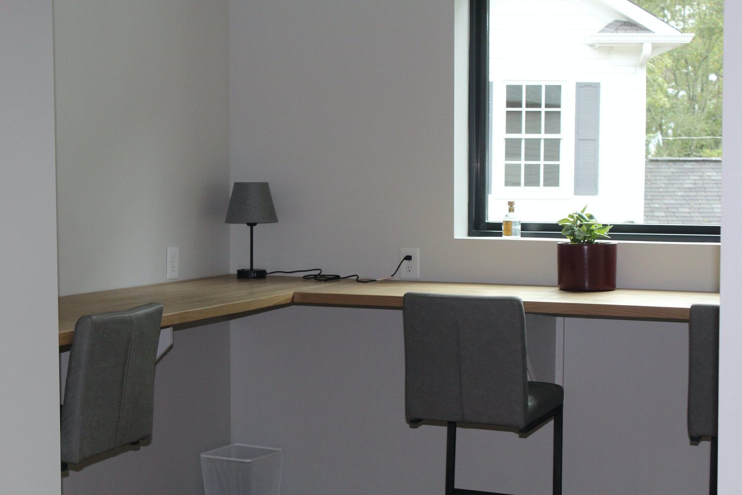 A row of desks along the wall under a window