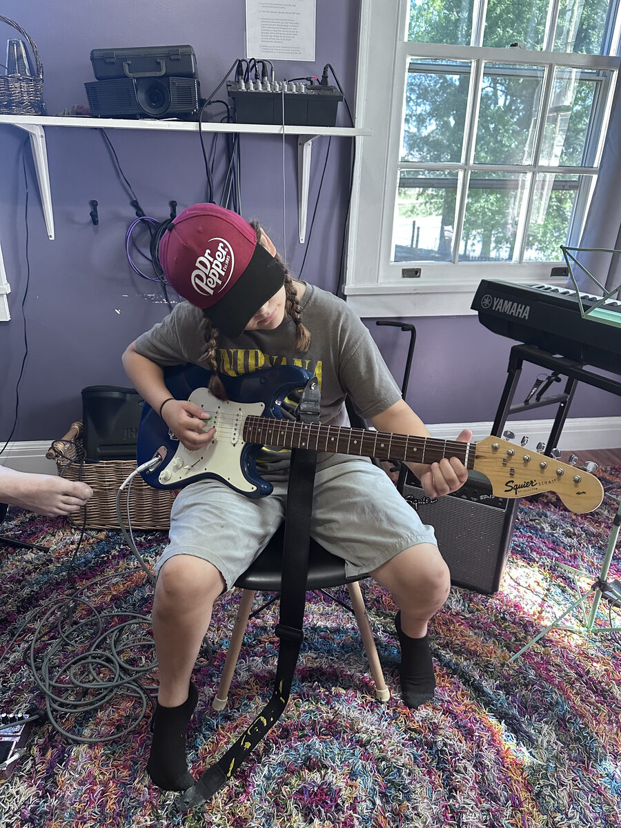 A kid practicing electric guitar in the music room