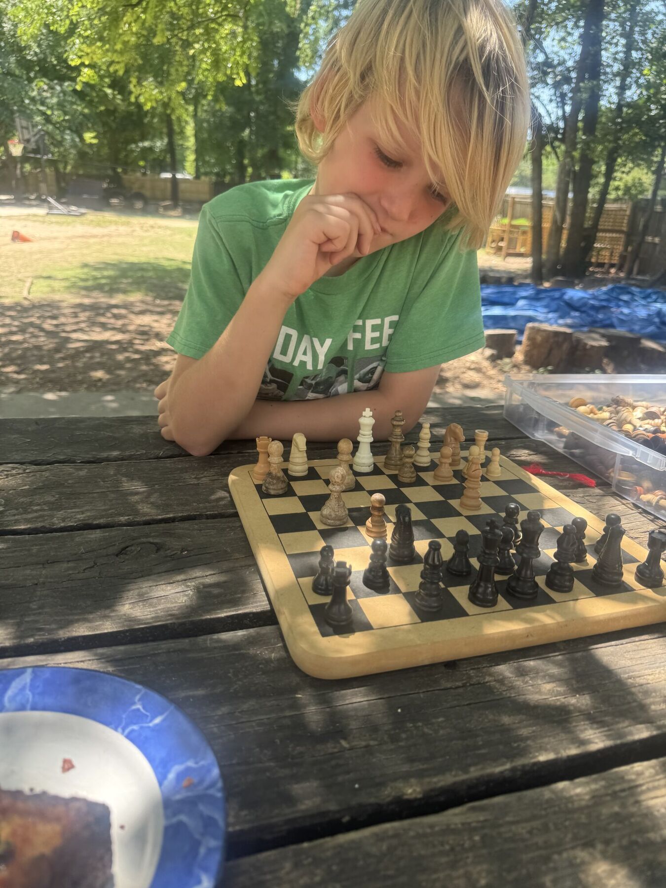 A kid thinking hard over an outdoor chess game