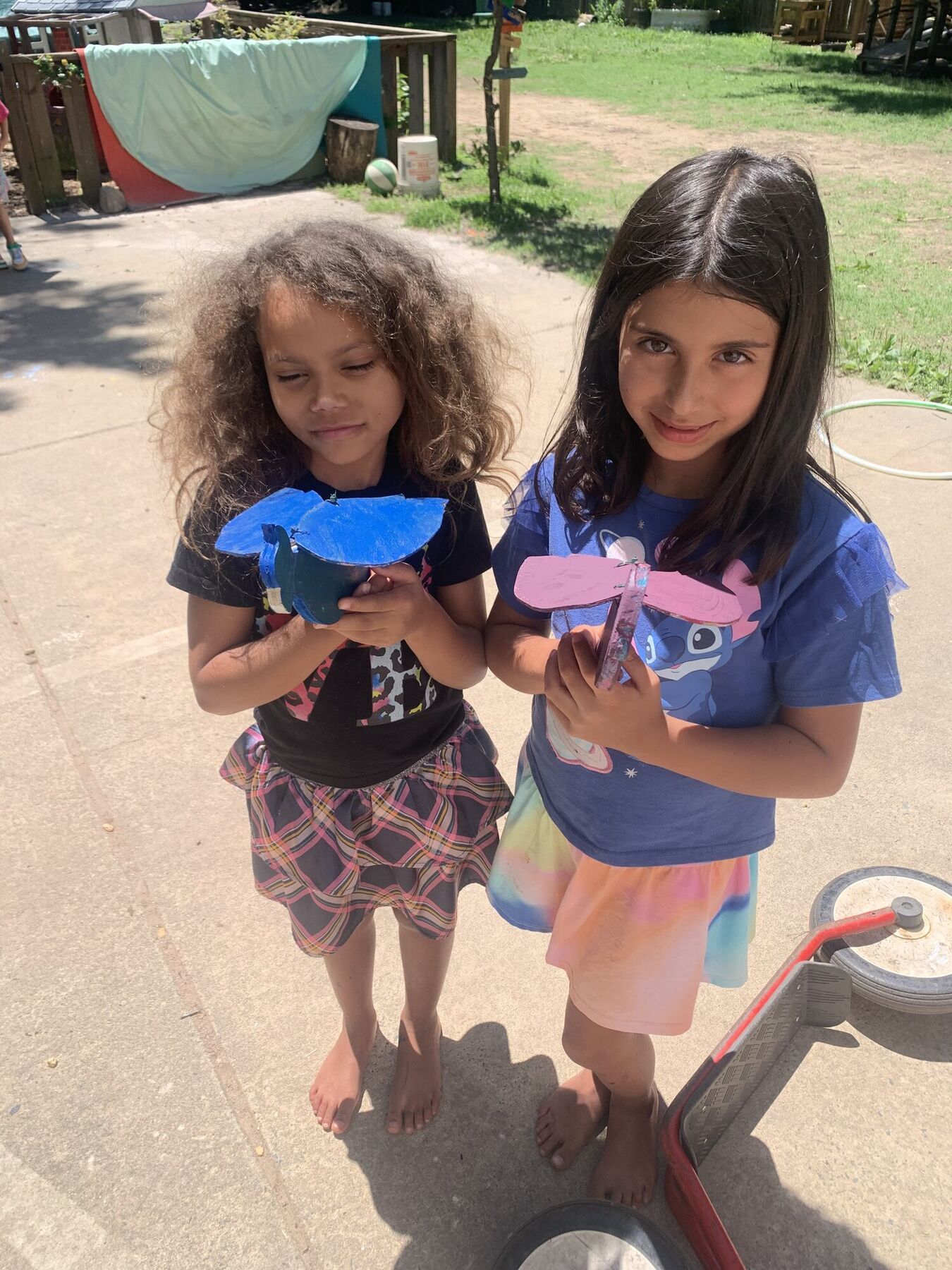 Two kids holding up the paper birds they made