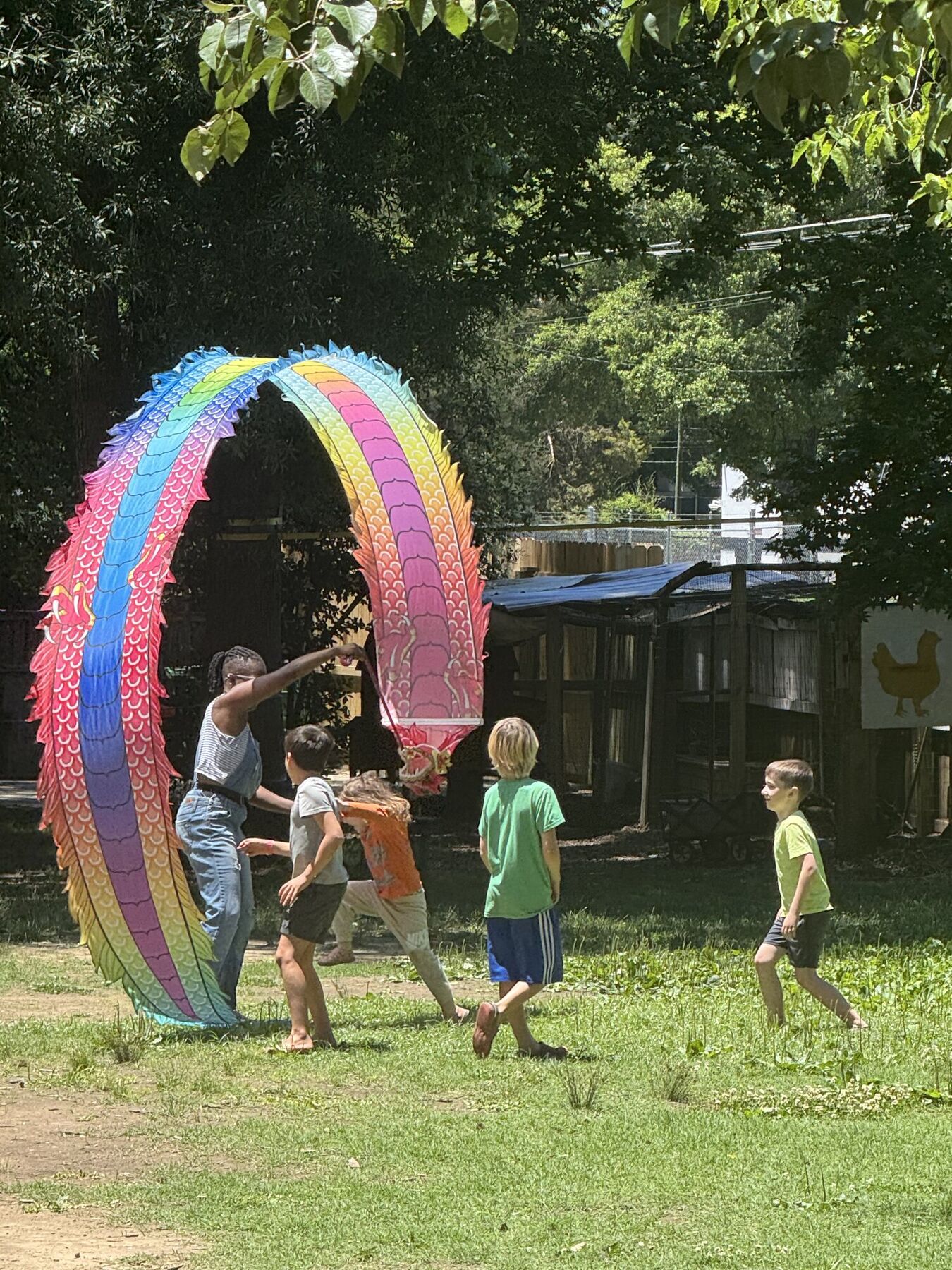 Kids running under a rainbow arch sculpture in the grass