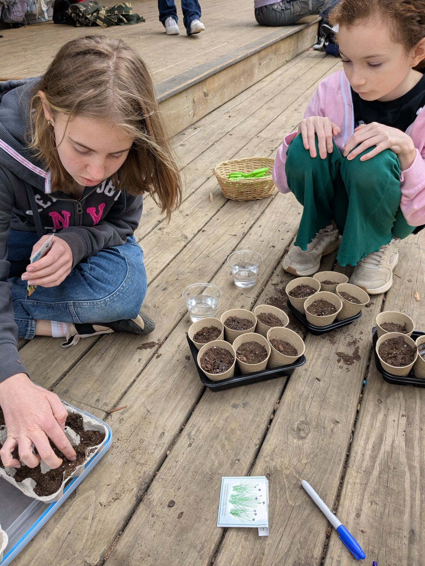 Kids planting seeds in pots on the deck