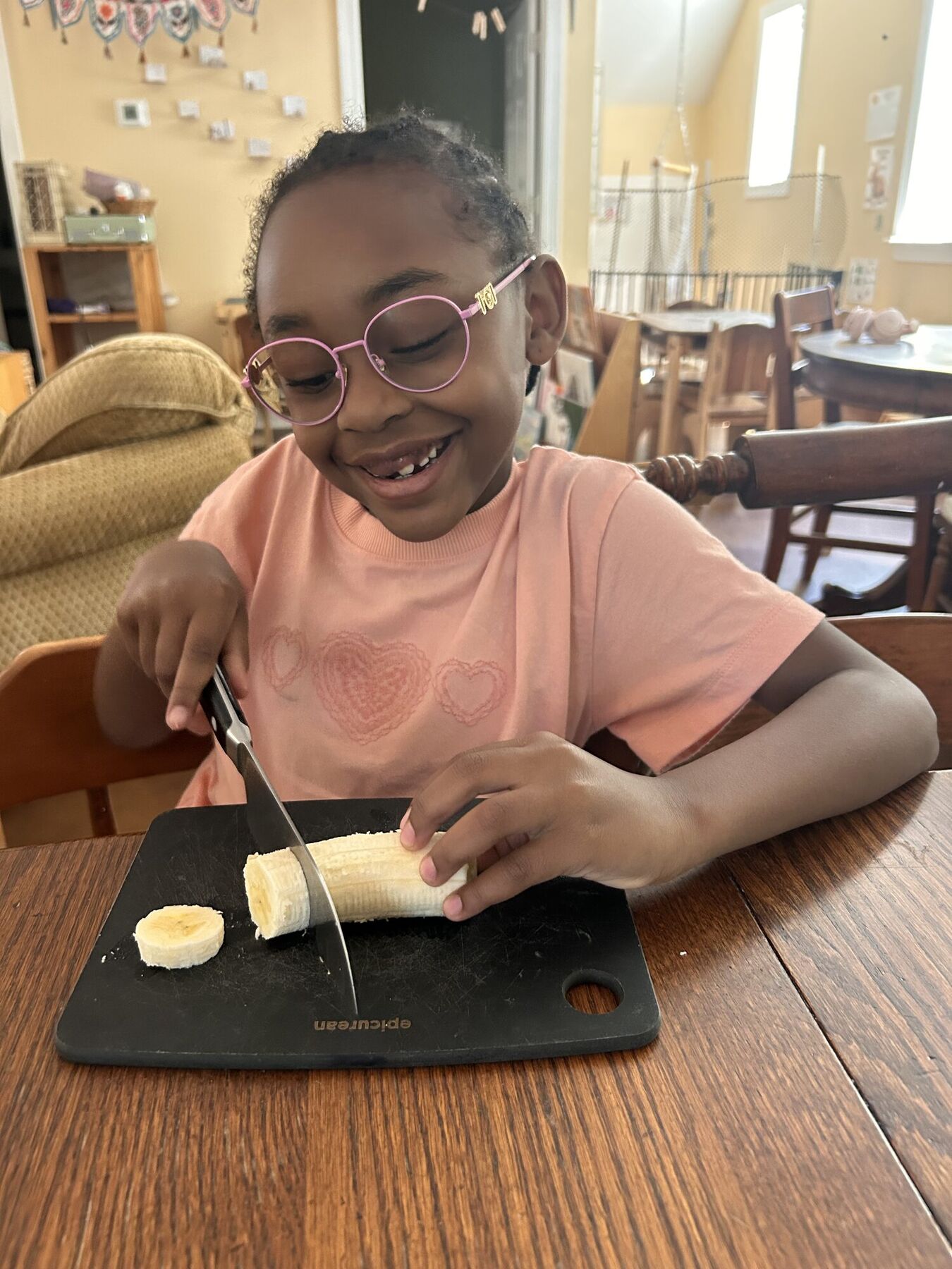 A kid slicing a banana, smiling